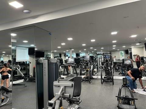 Interior view of a fitness gym with various exercise equipment and mirrors.