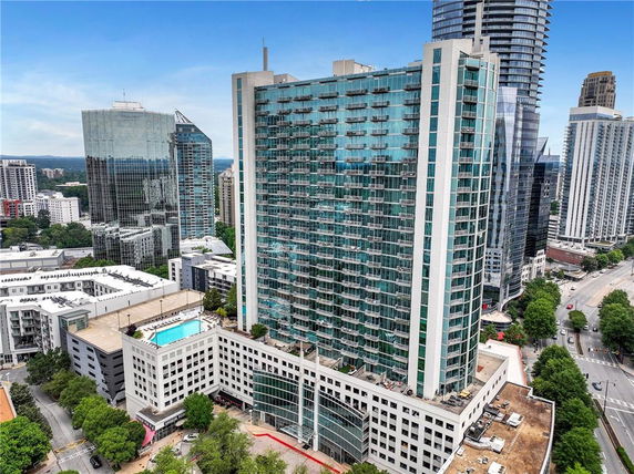 Front view of a high-rise building with glass balconies and adjacent structures.