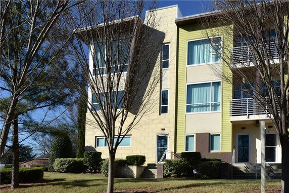 Front view of a multi-story modern apartment building with large windows and a mix of yellow and beige exterior walls.