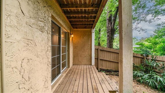 Wooden patio area with a view of a wooden fence and surrounding greenery.