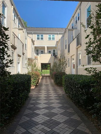 Front view of a multi-story residential building with paved walkways and balconies.