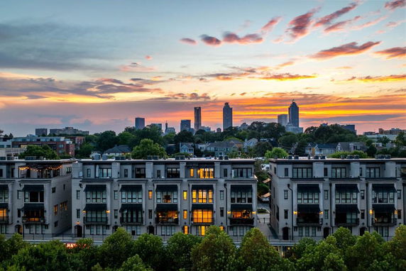 Panoramic view of residential buildings with a city skyline and sunset in the background.