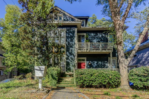 Front view of a two-story house with a porch and red front door.
