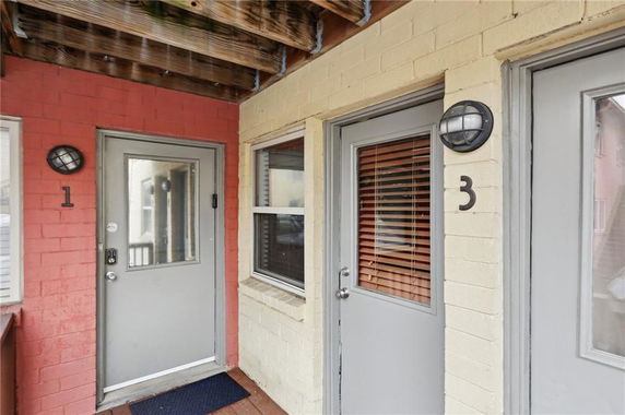 Entrance view of a building with numbered doors and brick walls.