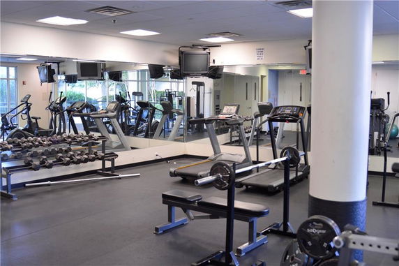 Indoor gym with exercise equipment including treadmills and weight benches.