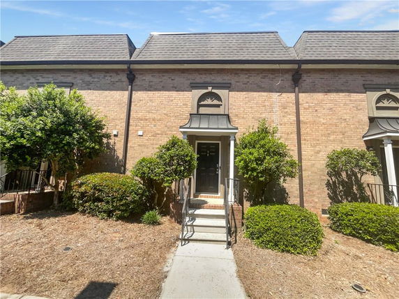 Front view of a two-story brick townhouse with a centered black entrance door.