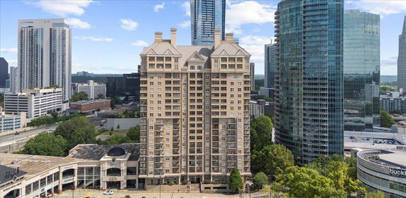 Front view of a tall apartment building with multiple floors and chimneys, surrounded by other skyscrapers.