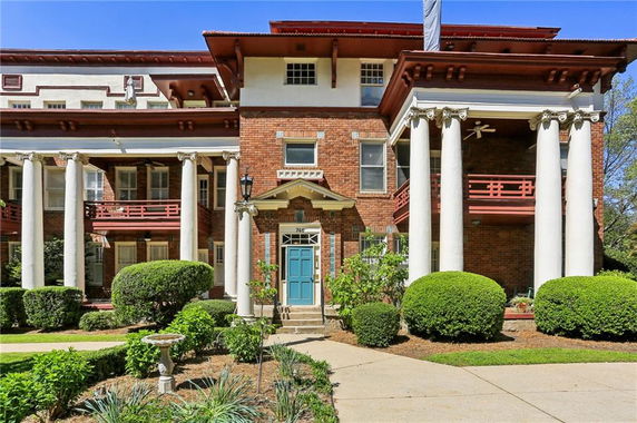 Front view of a multi-story brick house with large columns and a blue door.