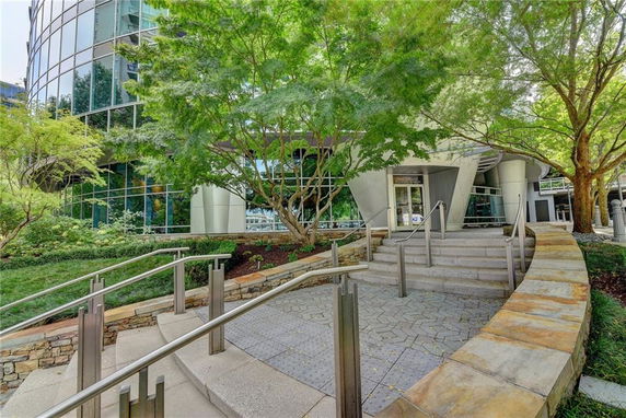 Front view of a modern glass building with trees and steps leading to the entrance.