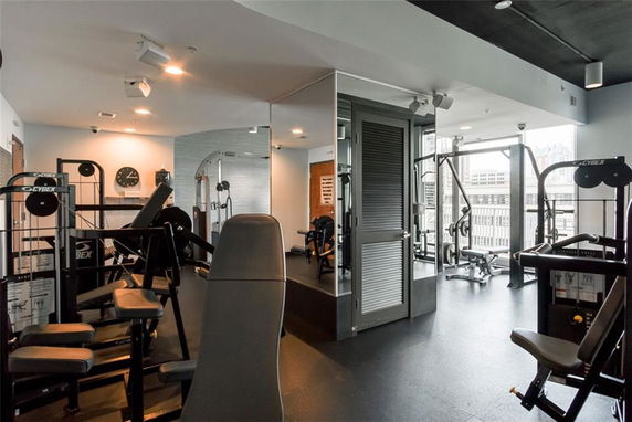Indoor gym area with various fitness equipment and mirrored walls.