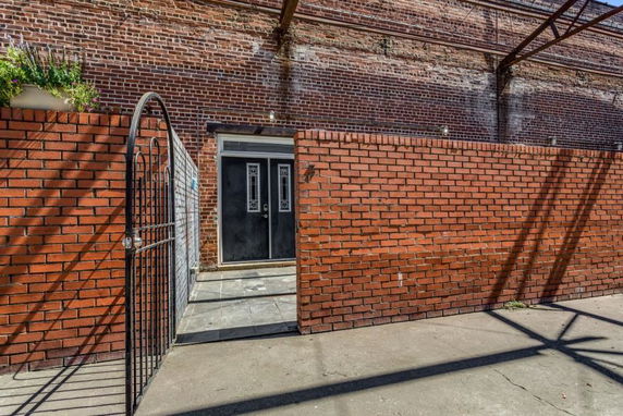 Entrance of a building with red brick walls and a metal gate.