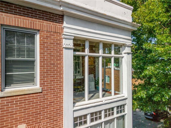 Corner view of a brick building with large windows and white decorative columns.