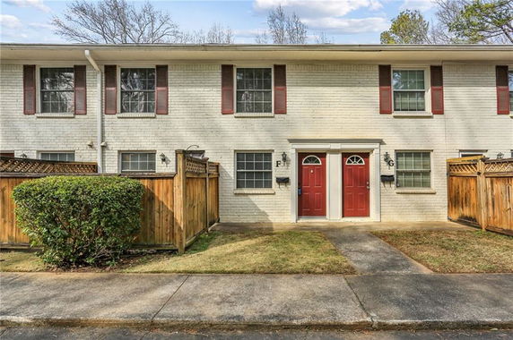Front view of a two-story brick house with two red doors.
