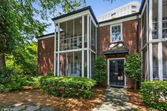 Front view of a brick house with screened balconies and black framed windows and door.