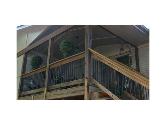 Front view of a house with a wooden balcony and hanging plants.