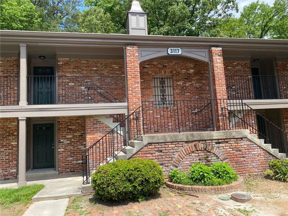 Front view of a two-story brick building with stairs and metal railings.