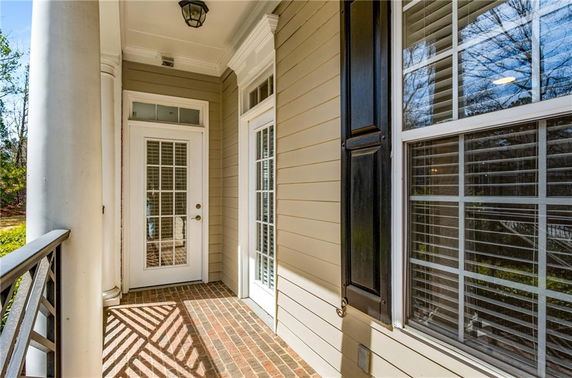 Front view of a house entrance with columns and brick flooring.