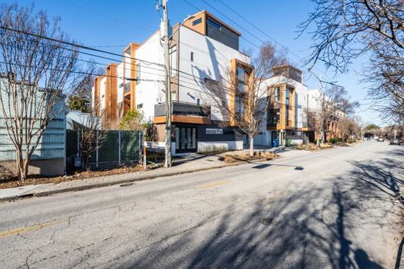 Street view of a modern multi-story building with a flat roof and large windows.