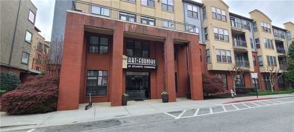 Front view of a multi-story building with a red brick facade and a sign reading 'The Art Foundry at Atlantic Commons.'