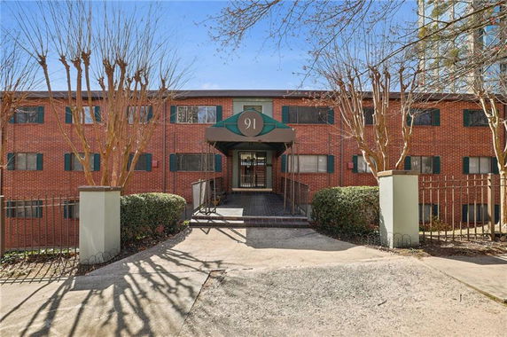 Front view of a multi-story brick building with green shutters and a canopy entrance.