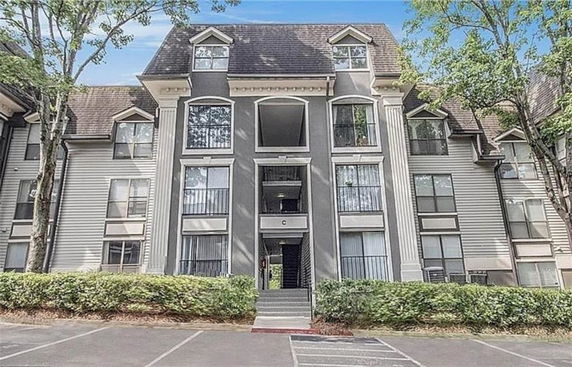 Front view of a multi-story residential building with large windows and gable roof.
