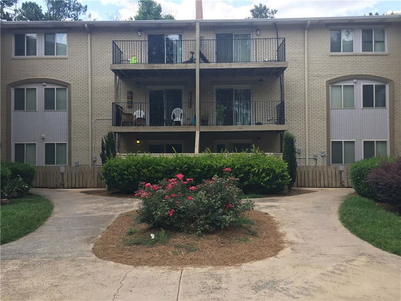 Front view of a multi-story building with balconies and brick exterior.