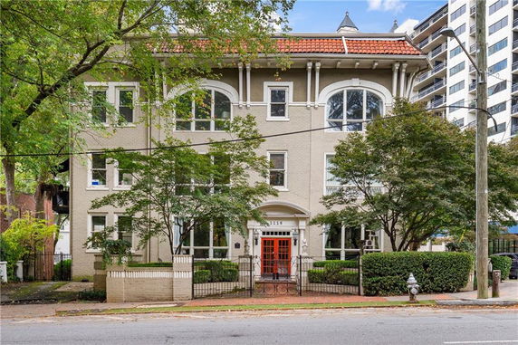 Front view of a three-story building with large windows and a red door.