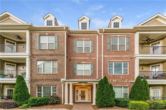 Front view of a three-story brick apartment building with balconies.