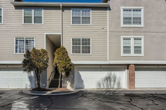 Front view of a multi-story townhouse with garages and exterior staircase.