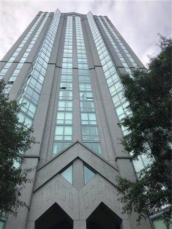 Front view of a tall multi-story building with large windows and a geometric facade.