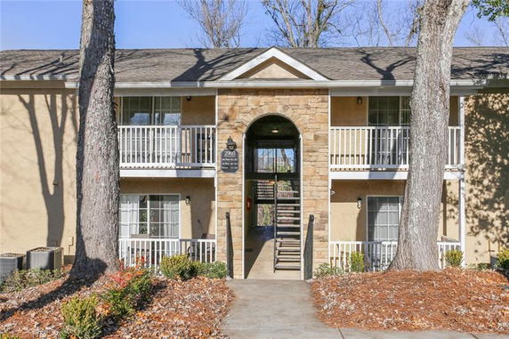 Front view of a two-story building with balconies and an arched stone entrance.