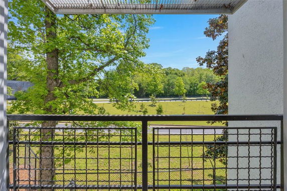 View from a balcony showing trees and open area.