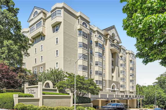 Front view of a multi-story residential building with arched windows and a covered entrance.