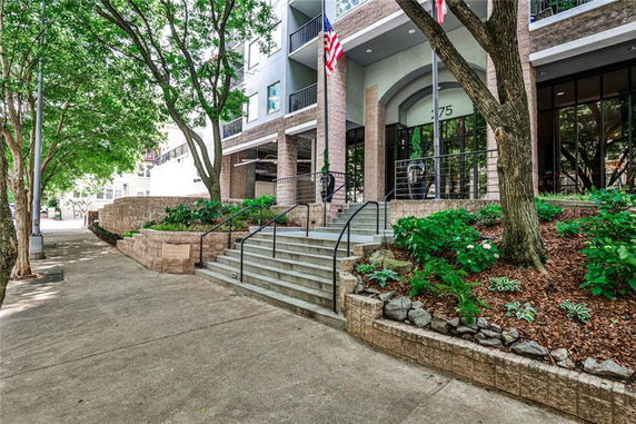 Front view of a multi-story building with steps and landscaped area leading to the entrance.
