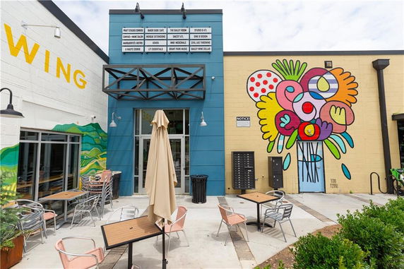 Front view of a building featuring a colorful mural and outdoor seating area.