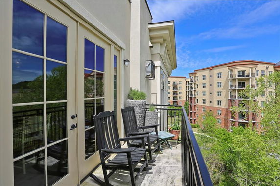 Balcony with chairs overlooking apartment buildings and greenery.