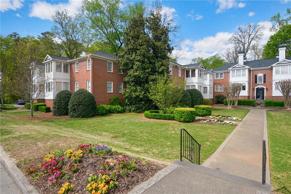 Front view of a two-story brick apartment building with landscaped gardens.