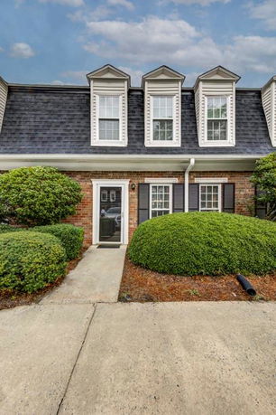 Front view of a two-story brick townhouse with dormer windows.