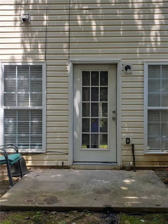 Back view of a house with a light-colored exterior and a glass door.