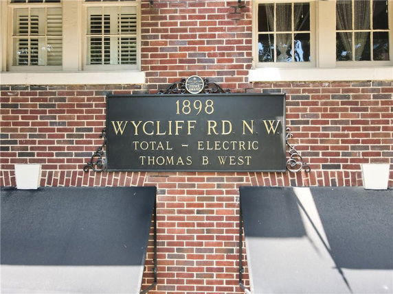 Front view of a brick building with a sign displaying address and year of establishment.