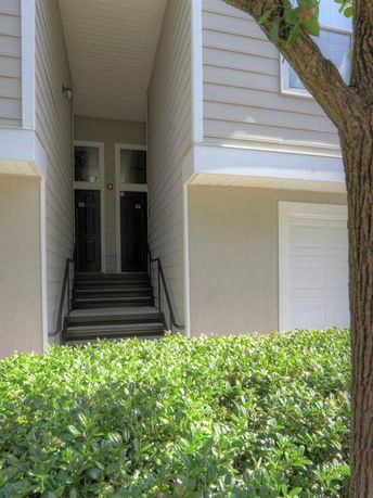 Front view of a multi-story building entrance with stairs leading to black doors.