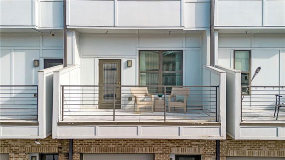 Front view of a building balcony with chairs and railing.