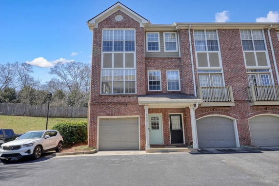 Front view of a multi-story brick townhouse with a garage.