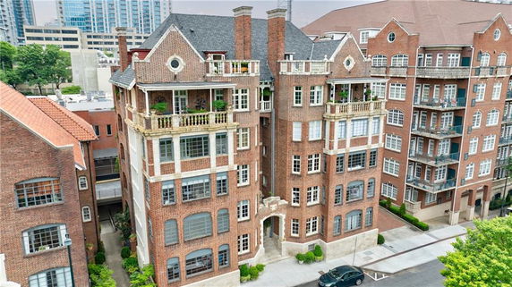 Front view of a multi-story brick building with decorative balconies and chimney stacks.