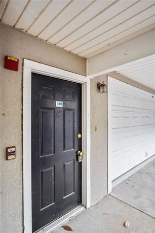 Front view of a building entrance with a black door and adjacent white garage door.
