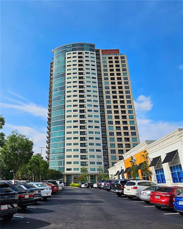 Front view of a high-rise building with a curved section and numerous windows.