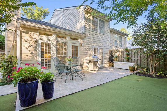 Backyard view of a two-story house with a patio area and outdoor seating.