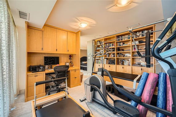 A room with exercise equipment and wooden shelves filled with books.