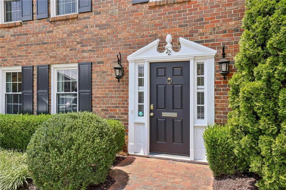 Front view of a brick house entrance with a black door and decorative trim.