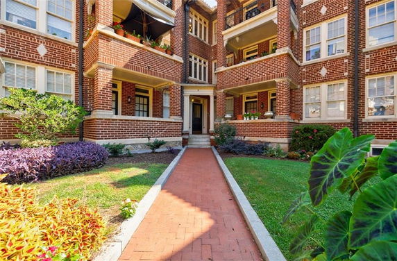 Front view of a multi-story brick apartment building with balconies and a central walkway.